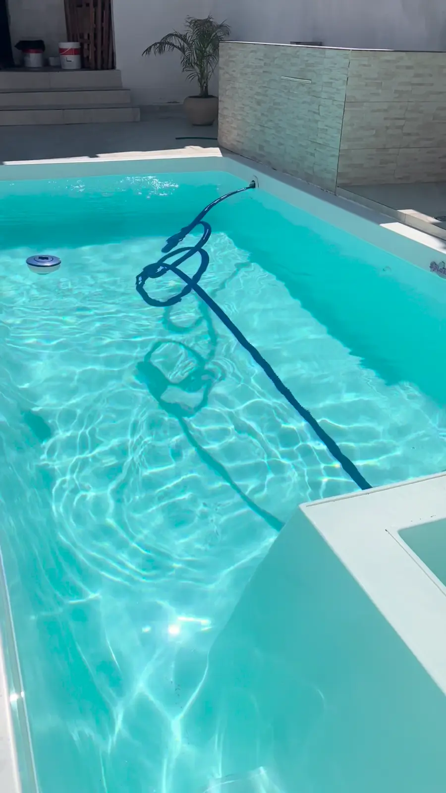 Água brilhando ao sol enquanto a piscina do Recanto Oásis é limpa com aspirador